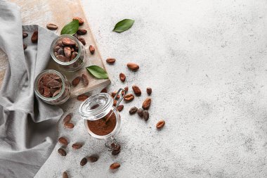 Kakao çekirdekleri, pudra ve çikolata ile Kavanozlar hafif arka plan üzerinde