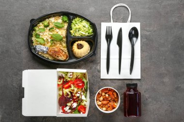 Gri arka planda lezzetli yemek ve çatal bıçak takımı içeren kaplar