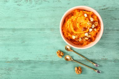 Ahşap arka plan üzerinde tatlı patates püresi ve fındık ile Bowl