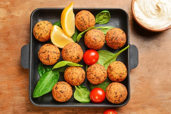 Frigideira com saborosas bolas de falafel e molho na mesa de madeira — Fotografia de Stock