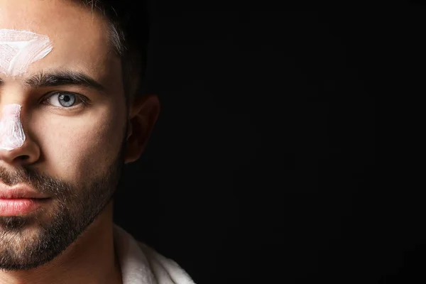 Handsome man with cosmetic clay on his face against dark background — Stock Photo, Image