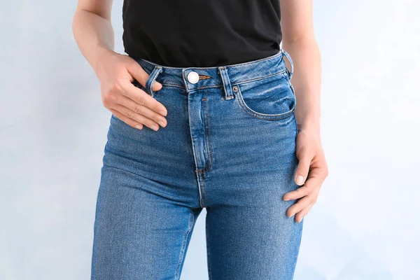 Jovem mulher vestindo calças jeans elegantes no fundo claro — Fotografia de Stock