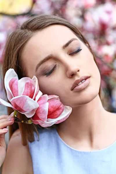 Porträtt av vacker ung kvinna nära blommande Magnolia träd utomhus — Stockfoto