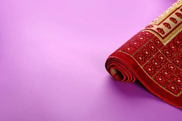 Muslim prayer rug on color background