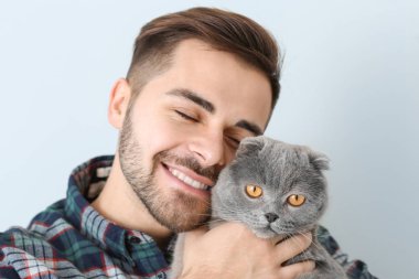 Hafif arka planda sevimli kedisi olan genç bir adam.
