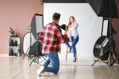 Stüdyoda modelle çalışan genç bir erkek fotoğrafçı.