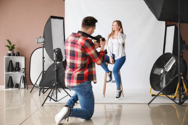 Stüdyoda modelle çalışan genç bir erkek fotoğrafçı.