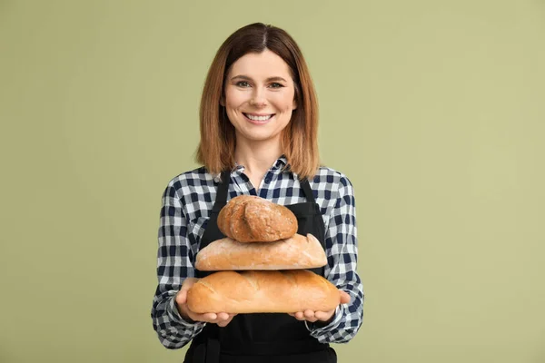 Female baker with bread on color background — Stock Photo, Image