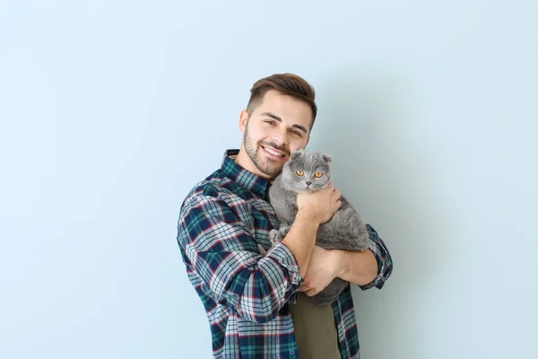 Молодой человек с милой забавной кошкой на светлом фоне — стоковое фото