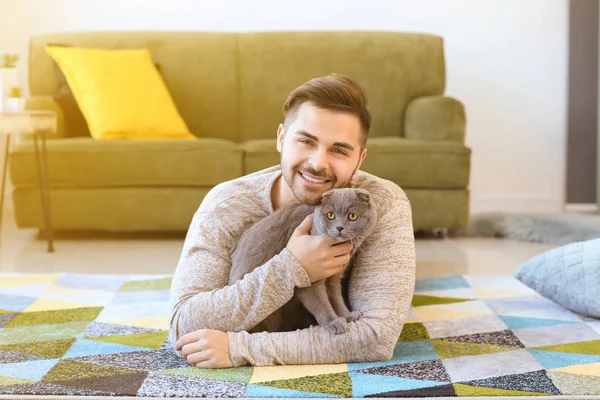 Young man with cute funny cat at home — Stock Photo, Image