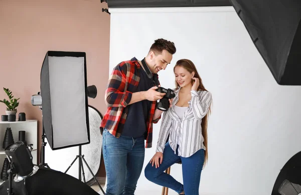 Manlig fotograf visar unga modell hennes bilder i studion — Stockfoto