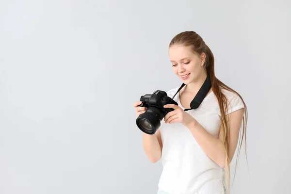 Young female photographer on light background — Stockfoto