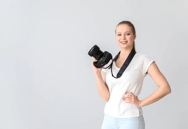 Young female photographer on light background — Stock Photo, Image