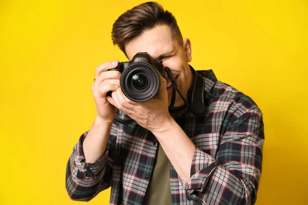Jonge mannelijke fotograaf op kleur achtergrond — Stockfoto