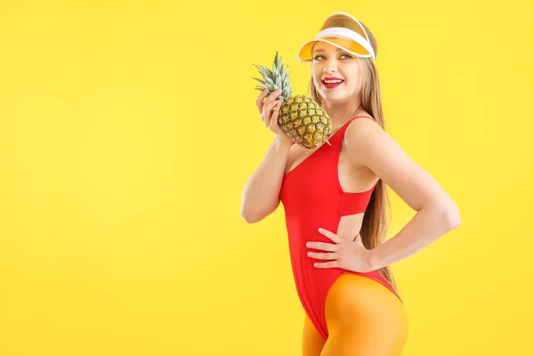 Schöne junge Frau in Badeanzug und mit Ananas auf farbigem Hintergrund — Stockfoto