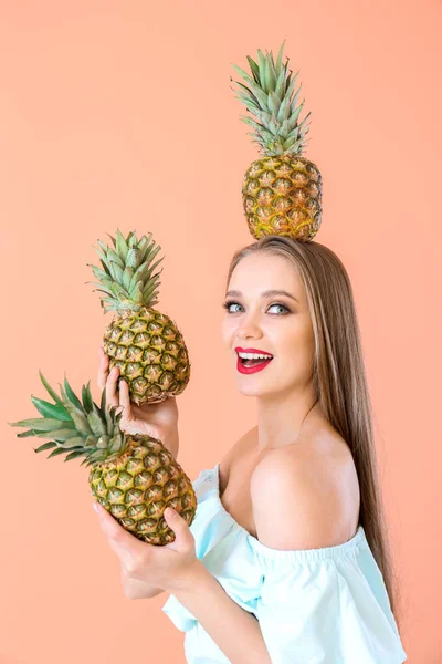 Beautiful young woman with pineapples on color background — Stock Photo, Image