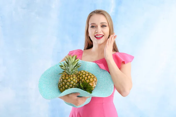 Hermosa mujer joven con piñas sobre fondo de color — Foto de Stock