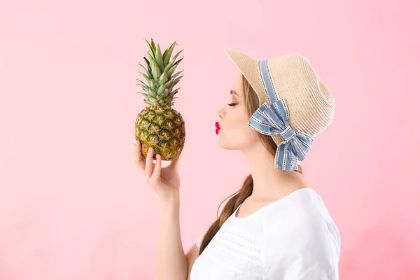 Mooie jonge vrouw met ananas op kleur achtergrond — Stockfoto