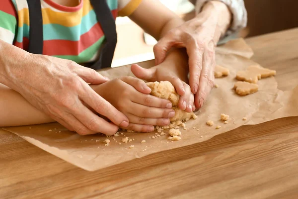 Niña con su abuela cocinando galletas en la mesa, primer plano — Foto de Stock