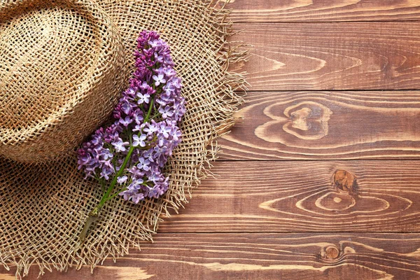Beautiful lilac flowers and hat on wooden background — Stock Photo, Image