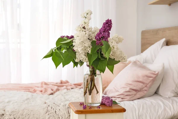 ベッドルームでテーブルの上に美しいライラックの花と花瓶 — ストック写真