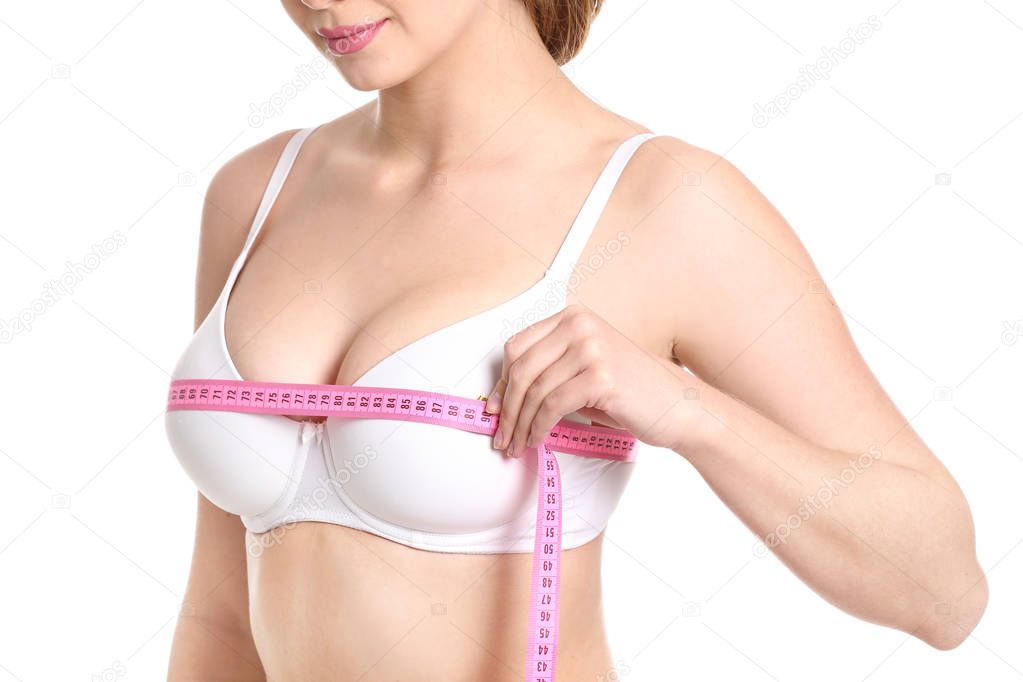 Young woman measuring her breast on white background