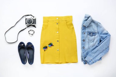 Beyaz arka planda aksesuarları ve fotoğraf kamerası ile şık kadın giysileri. Seyahat konsepti