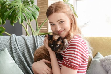Young woman with cute Thai cat at home
