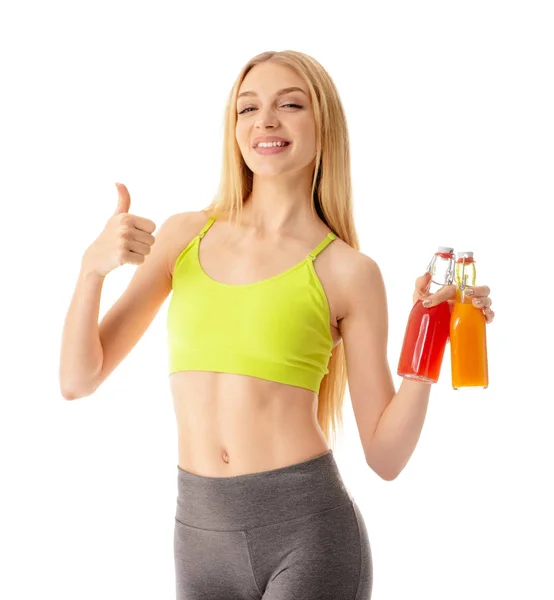 Спортивна молода жінка з пляшками соку показує великий палець на білому тлі — стокове фото