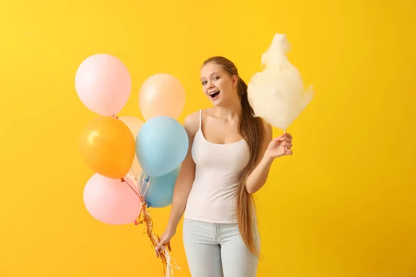 Schöne Frau mit Zuckerwatte und Luftballons auf farbigem Hintergrund — Stockfoto