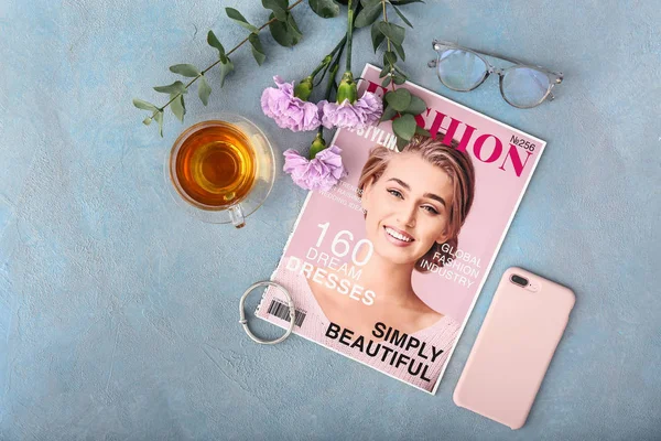 Revista de moda con teléfono móvil, flores, taza de té y accesorios femeninos sobre fondo de color — Foto de Stock