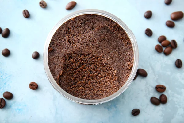 Jar with coffee body scrub on light background