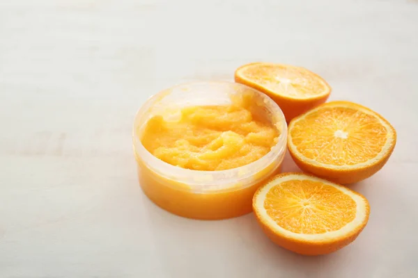 Jar with orange body scrub on light table — Stock Photo, Image