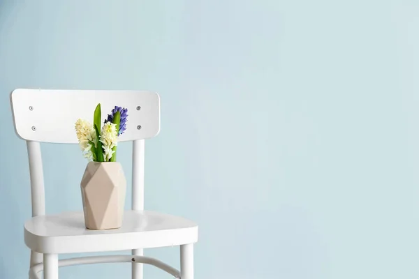 Βάζο με όμορφη Υάκινθος λουλούδια στην καρέκλα ενάντια στο φως τοίχου — Φωτογραφία Αρχείου