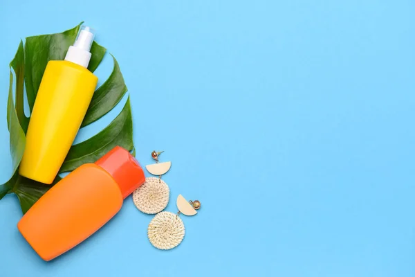 Cremas de protección solar con pendientes y hoja tropical sobre fondo de color — Foto de Stock