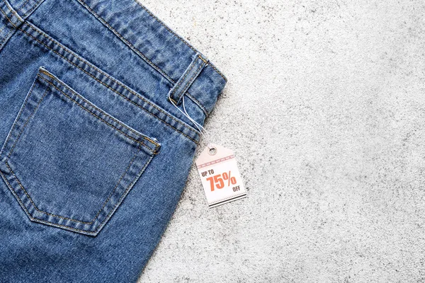 Stylish jeans with tag on light background — Stock Photo, Image