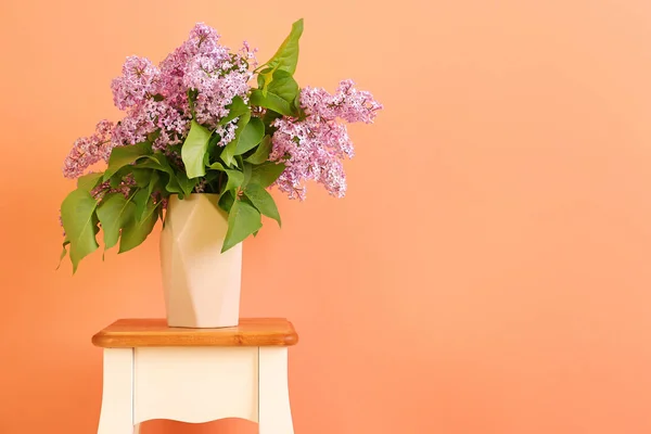 美丽的丁香花在桌子上的花瓶与颜色背景 — 图库照片