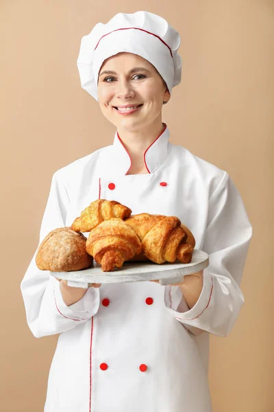 Female chef with bakery products on color background Royalty Free Stock Photos