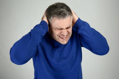 Yakışıklı olgun adam gri arka plan üzerinde korkunç baş ağrısı muzdarip