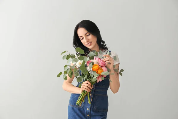 Portrait of beautiful woman with bouquet on light background — Stock Photo, Image