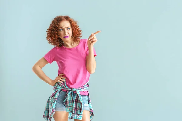 Stylish young woman pointing with finger on grey background — Stock Photo, Image