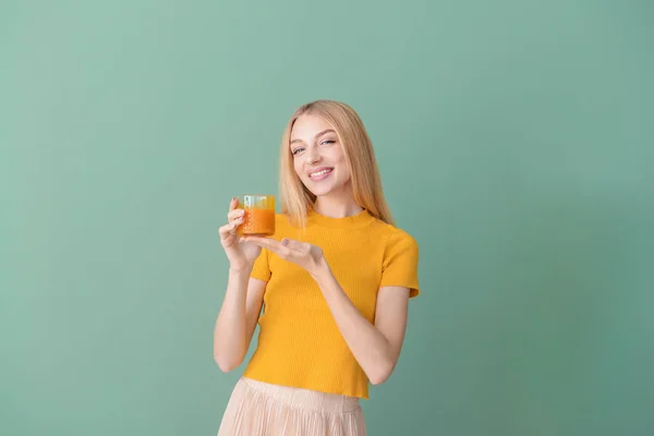 Schöne junge Frau mit frischem Saft auf farbigem Hintergrund — Stockfoto