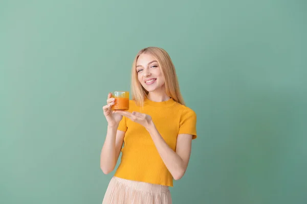 Hermosa mujer joven con jugo fresco en el fondo de color — Foto de Stock