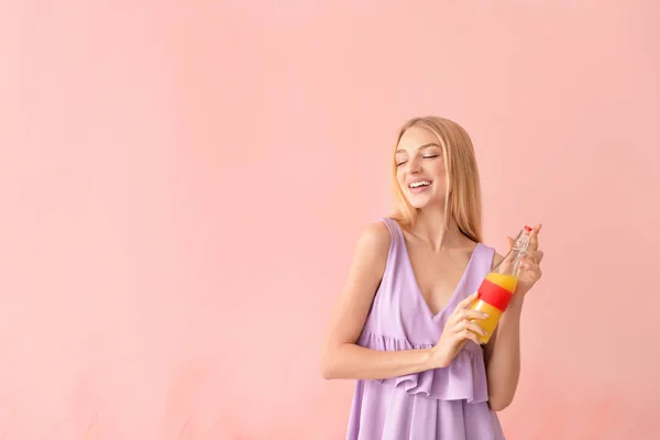 Mooie jonge vrouw met vers sap op kleur achtergrond — Stockfoto