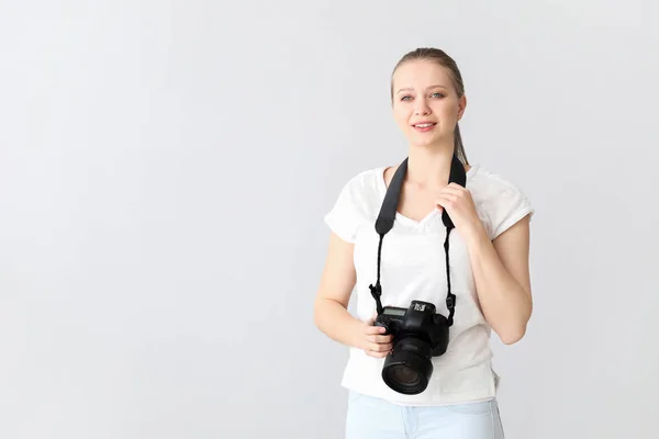 Young female photographer on light background — Stock Photo, Image