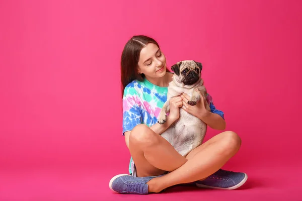 Menina adolescente com cão pug bonito no fundo de cor — Fotografia de Stock