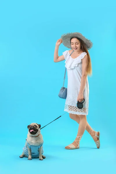 Девочка-подросток с милой собакой-мопсом на цветном фоне — стоковое фото