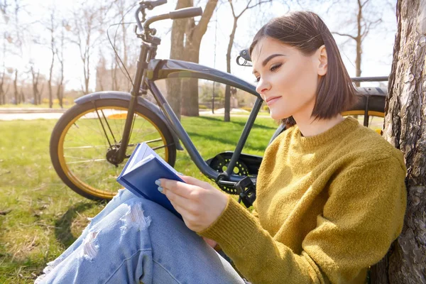 Mooie jonge vrouw lezen boek in Park op de lente dag — Stockfoto