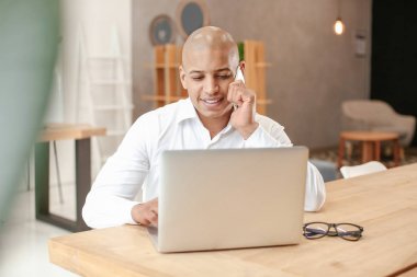 Yakışıklı Afro-Amerikan adam ofiste dizüstü bilgisayar üzerinde çalışıyor