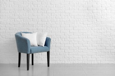 Beyaz tuğla duvara karşı koltukta yumuşak yastıklar